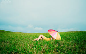 Gadis di rumput dengan payung beristirahat di latar belakang geser